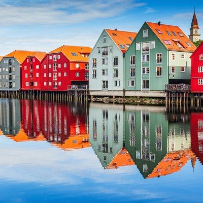 Kleurrijke pakhuizen aan de kade in Trondheim, Noorwegen, met spiegeling in het water.
