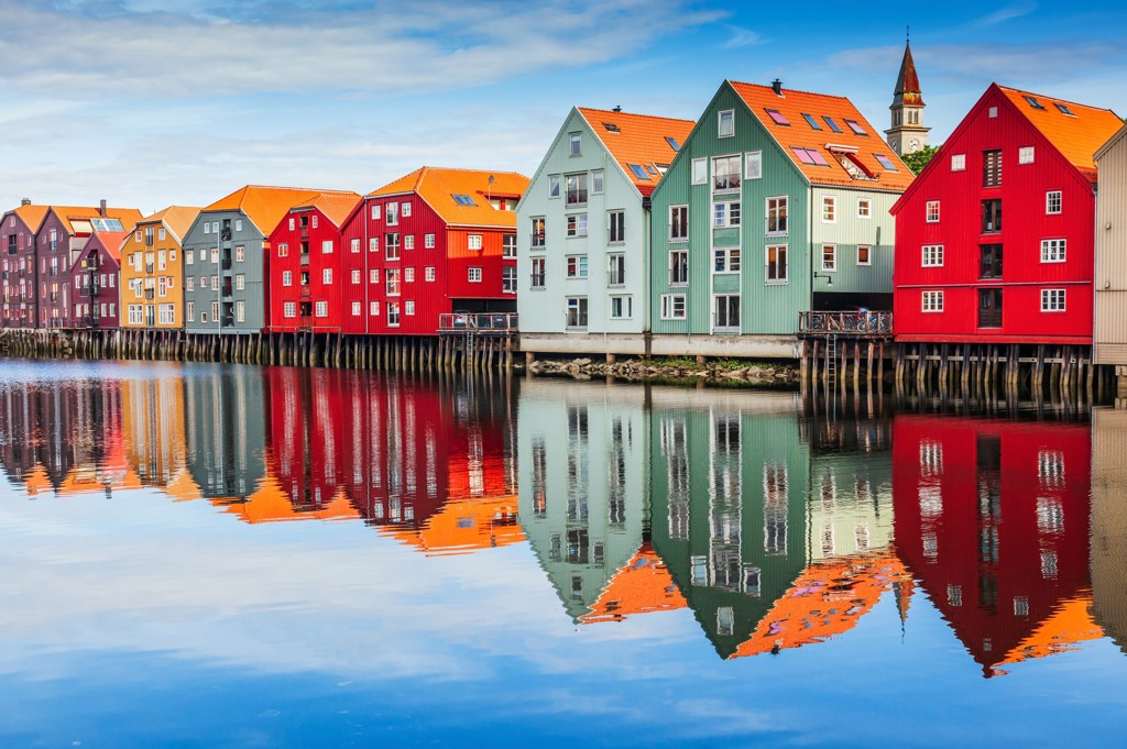 Kleurrijke pakhuizen aan de kade in Trondheim, Noorwegen, met spiegeling in het water.