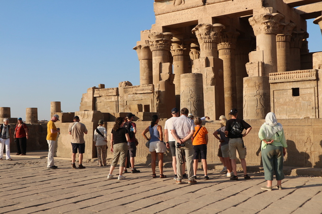 Reizigers tijdens een groepsrondreis Egypte bij een tempel met hoge zuilen en reliëfs.