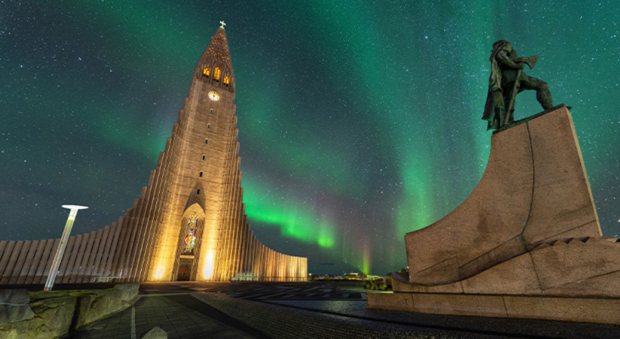 Noorderlicht in Reykjavik, IJsland Noorderlicht boven de Hallgrímskirkja in Reykjavik, met standbeeld op de voorgrond.
