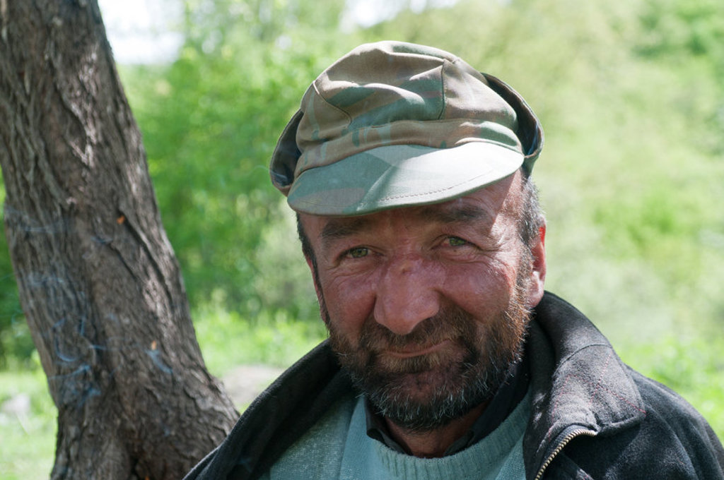 Portret van een man met pet in het groene landschap van Georgië.