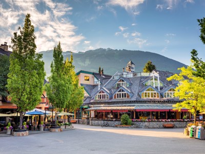 Dorpsplein in Whistler met hotelgebouwen en terrasjes, met bergen op de achtergrond tijdens de Route Canada.