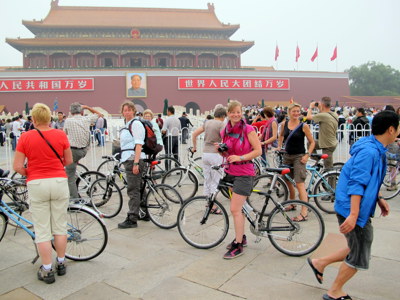 Fietsers en toeristen op het Tiananmenplein in Beijing, met de Poort van de Hemelse Vrede op de achtergrond.