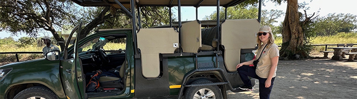 Reiziger bij open safariwagen tijdens safari in Zuidelijk Afrika.