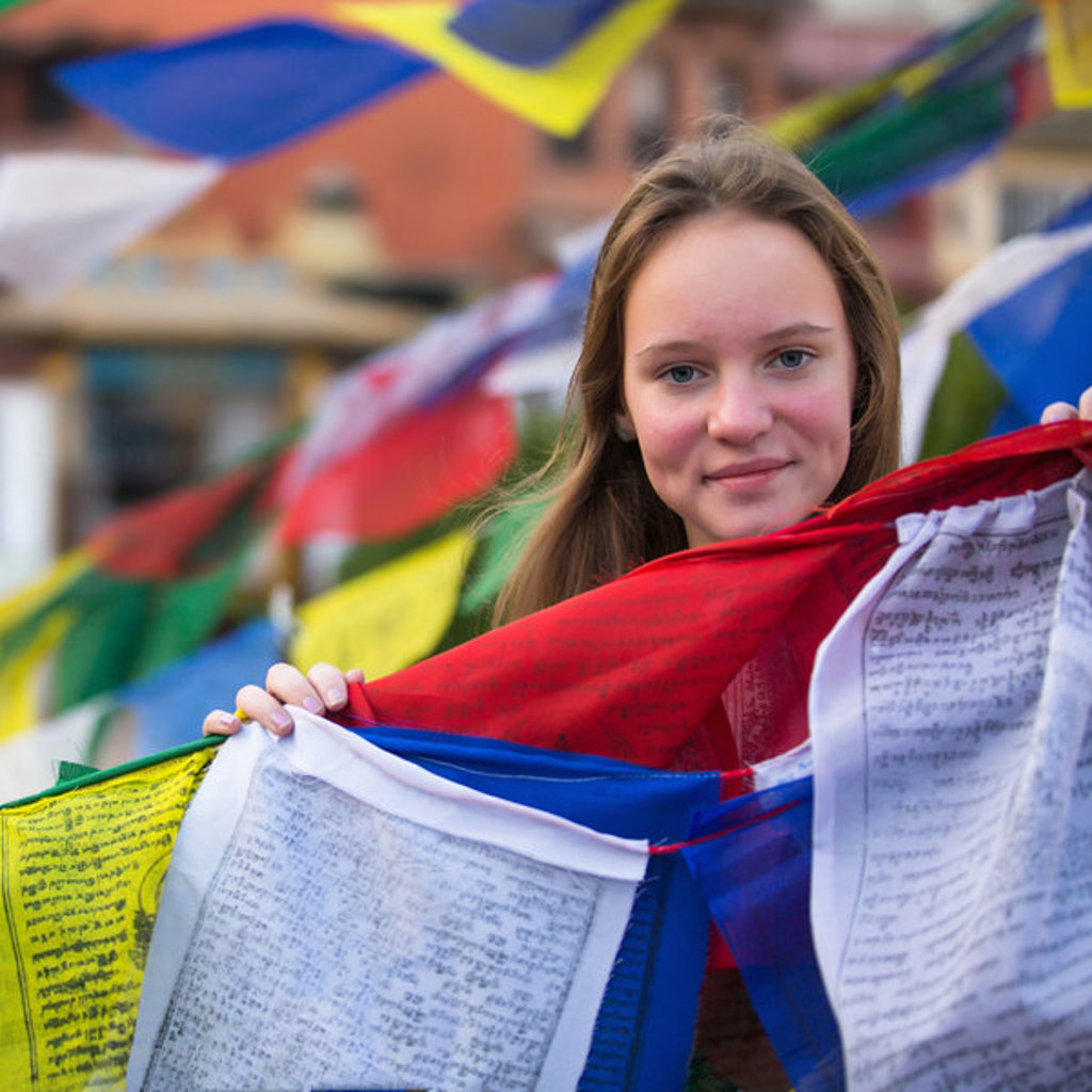 Meisje met kleurrijke gebedsvlaggen in Nepal tijdens een familiereis.