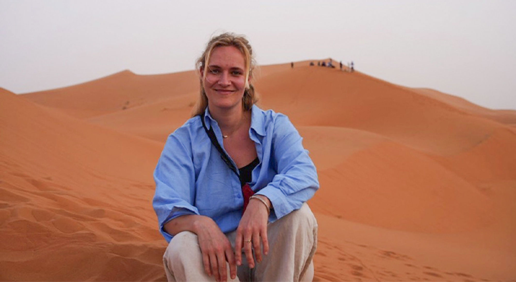 Ankie in Marokko Vrouw zit in zandduinen in de woestijn bij zonsondergang.