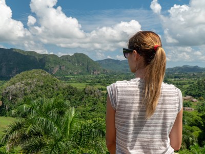Reiziger kijkt uit over de groene Viñales-vallei met mogotes in Cuba.