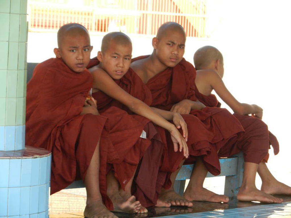 Jonge boeddhistische monniken in rode gewaden bij een tempel in Myanmar.