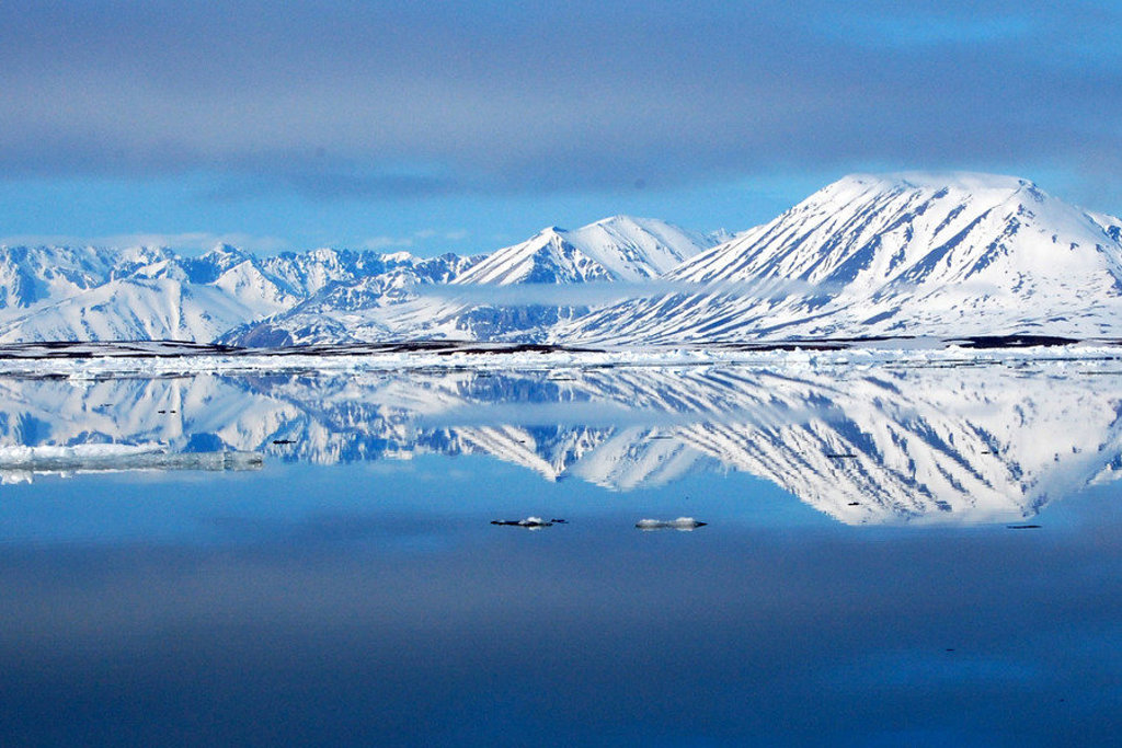Besneeuwde bergen en gletsjers op Spitsbergen weerspiegeld in een stille fjord tijdens de rondreis Vier Arctische eilanden.