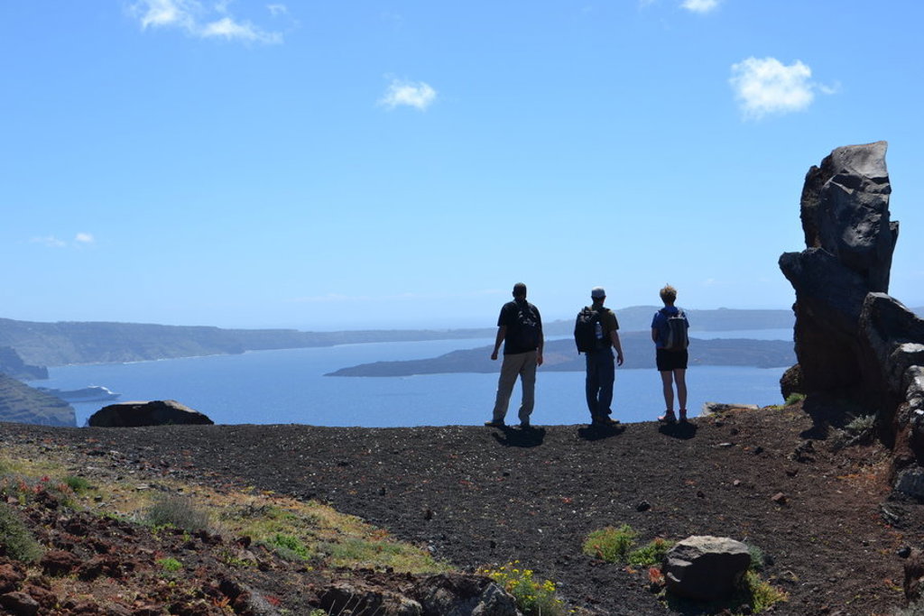 Wandelaars met rugzakken kijken uit over de caldera op Santorini tijdens wandelvakantie Griekenland.