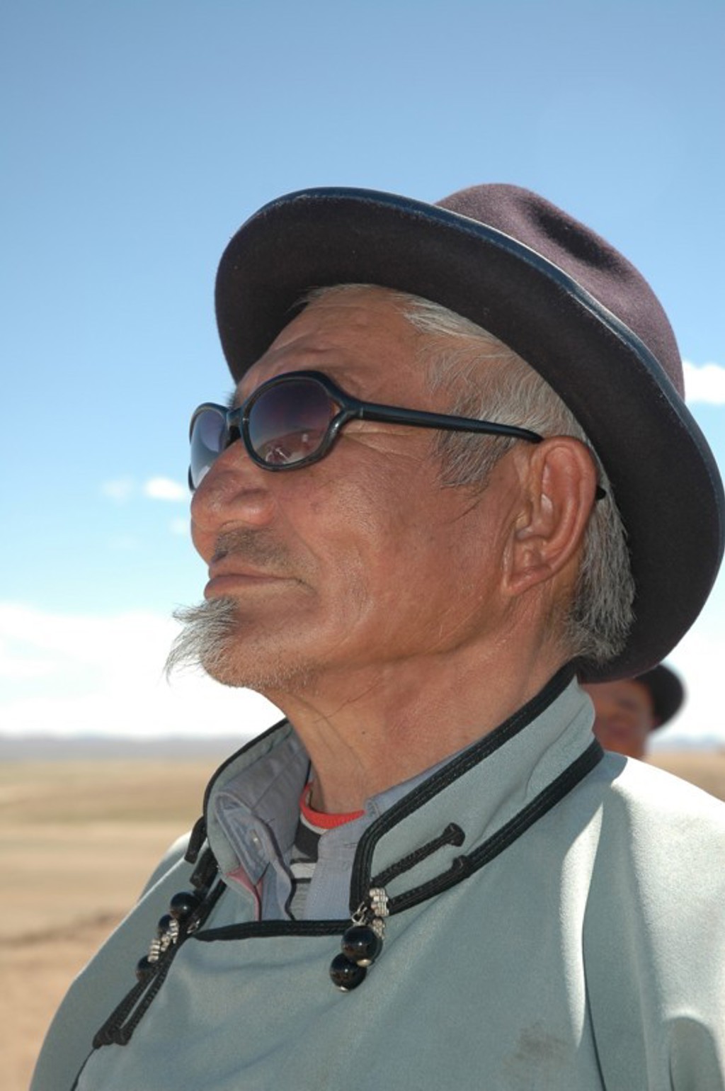 Portret van een Mongoolse man met hoed en zonnebril tijdens een groepsrondreis door Mongolië.