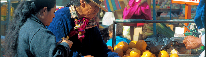 Peruaanse markt met verkopers bij een kraam vol sinaasappels.