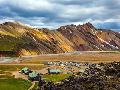 Camping en berghutten in Landmannalaugar, met kleurrijke rhyolietbergen en rivierdelta op de achtergrond, IJsland.