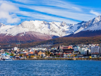 Ushuaia aan het Beaglekanaal met kleurrijke gebouwen en besneeuwde Andesbergen op de achtergrond.