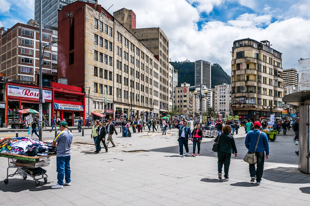 Drukke straat in Bogotá, Colombia, met marktkramen, voetgangers en hoge gebouwen.