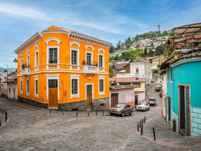Kleurrijke straat in Quito met feloranje  pand en uitzicht op de heuvels.