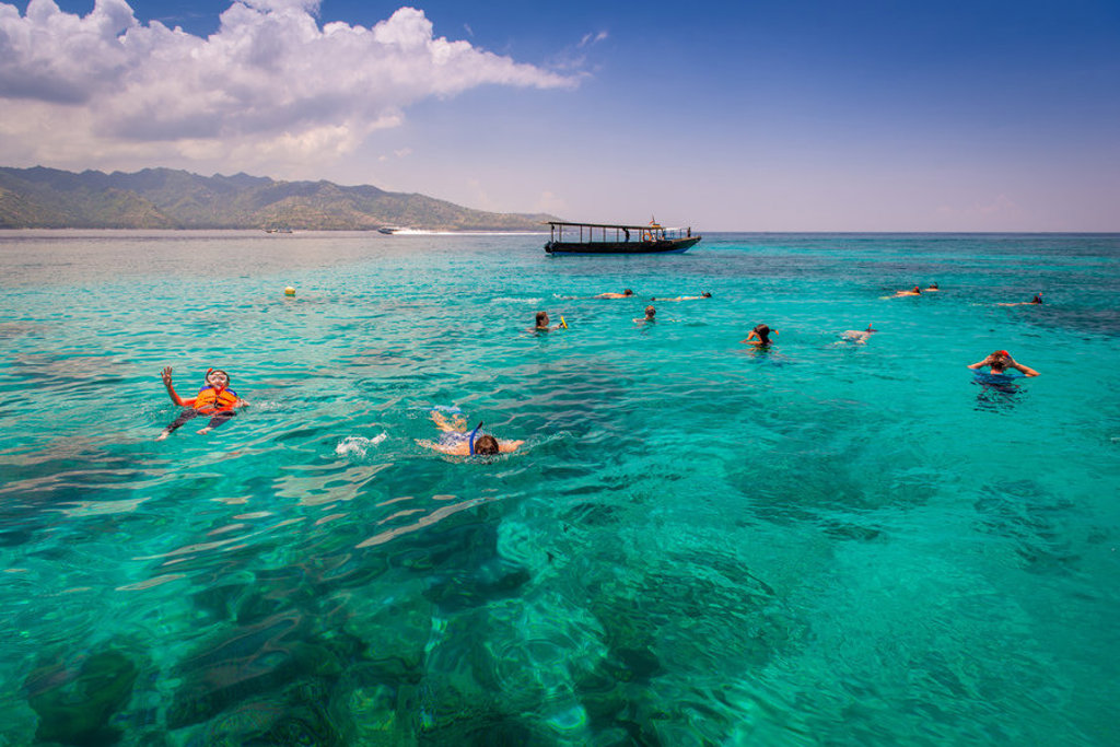 Snorkelen in helderblauw zeewater bij Bali tijdens een 22-35ers reis Indonesië, met boot op de achtergrond.