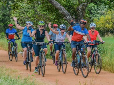 Groep fietsers tijdens een fietsvakantie in Sri Lanka op een onverharde weg door groen landschap.