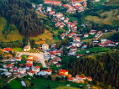 Bergdorp in de Bulgaarse Balkan met roodgedekte huizen tussen groene heuvels en dennenbossen.
