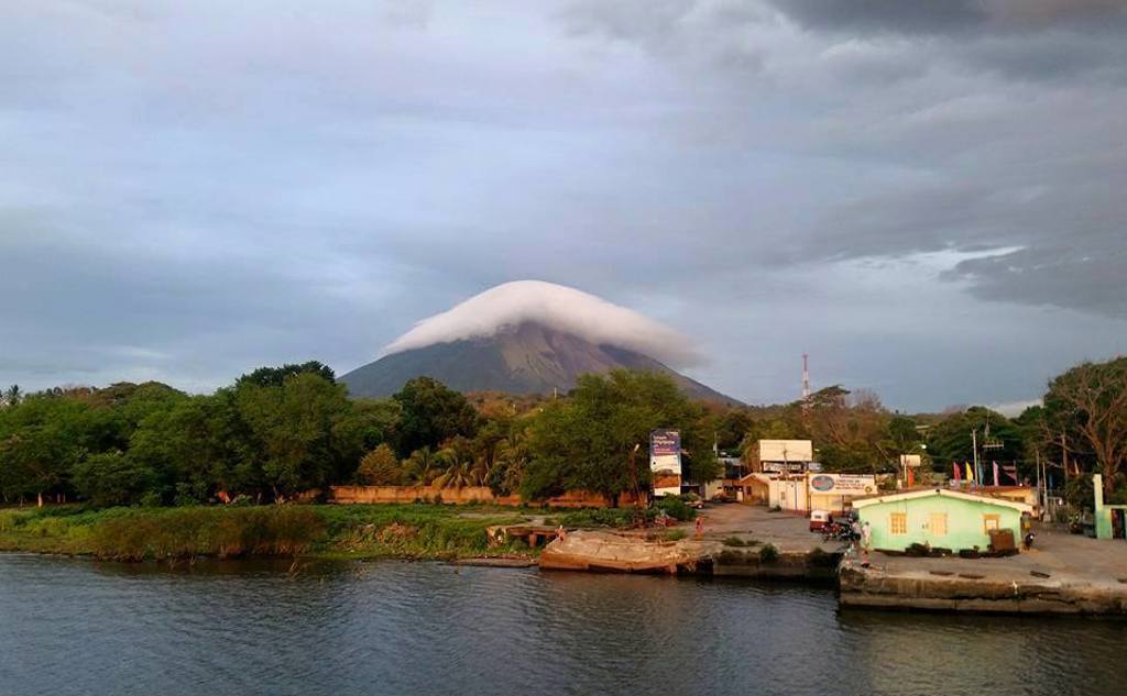 Vulkaan Concepción op Isla de Ometepe aan het Meer van Nicaragua, met wolkenkap en oeverdorp.