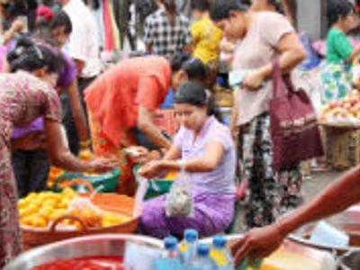 Drukke markt in Myanmar met mensen die vers fruit en etenswaren kopen bij kraampjes.