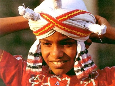Portret van een man in traditionele Sri Lankaanse kledij met witte tulband en rood gewaad.