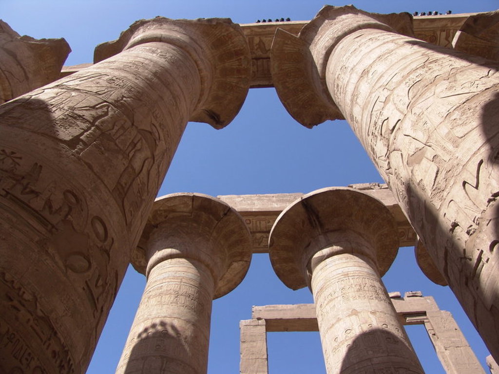 Zuilen met hiërogliefen bij een Egyptische tempel, gezien van onderaf tegen een blauwe lucht.