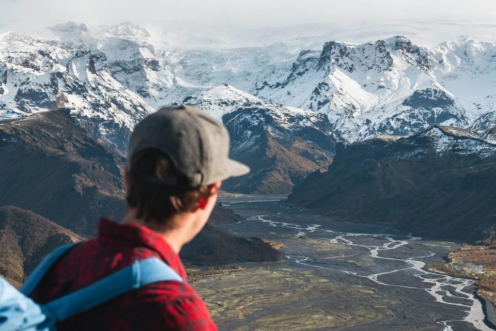 Groepsreis 22-35ers in IJsland met uitzicht op bergen en een waterval.