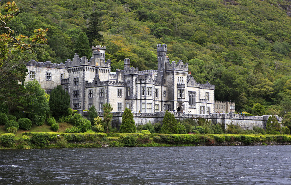 Kylemore Abbey aan het water, omringd door groene heuvels in Ierland.