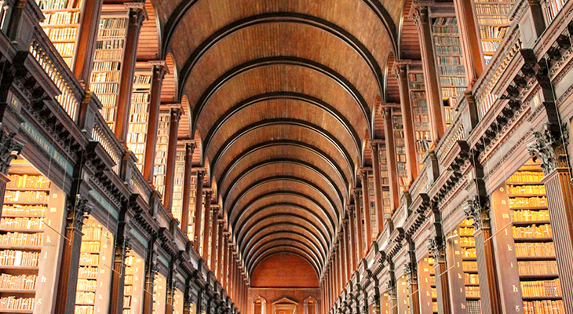 Trinity Library, Dublin, Ierland Interieur van een historische bibliotheek met hoge boekenkasten en een lang gewelfd plafond.