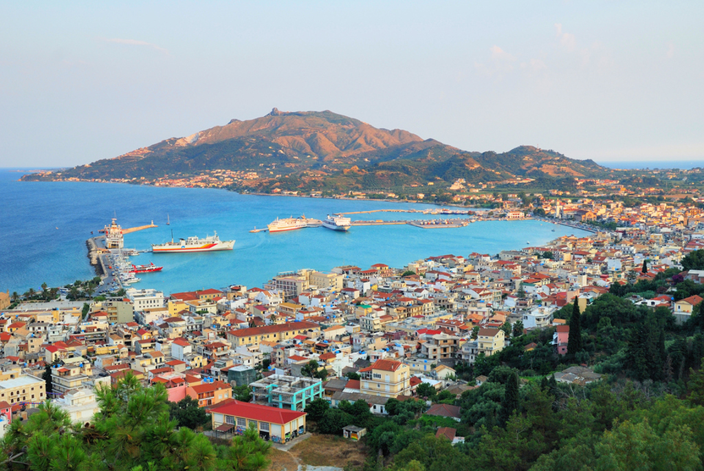 Uitzicht op havenstad Zakynthos met veerboten en bergen aan zee tijdens 22-35ers reis Griekenland.