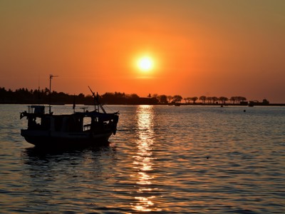 Zonsondergang boven zee met vissersboot in silhouet, Bali & Sulawesi-route.