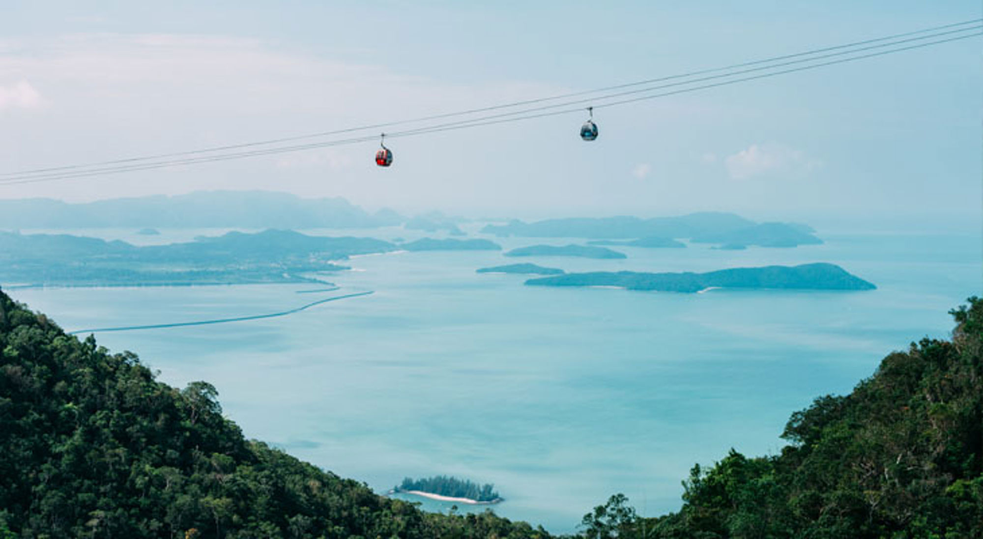 Langkawi Maleisië Kabelbaan met gondels boven zee met eilanden, gezien vanaf een groen berglandschap.
