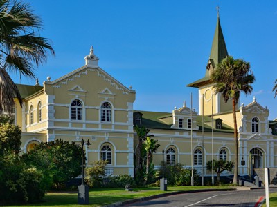 Historisch gebouw in Windhoek, Namibië, met toren en palmbomen langs de weg.