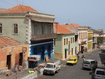 Straat in Mindelo, Kaapverdische eilanden, met kleurrijke koloniale huizen en passerende auto’s.