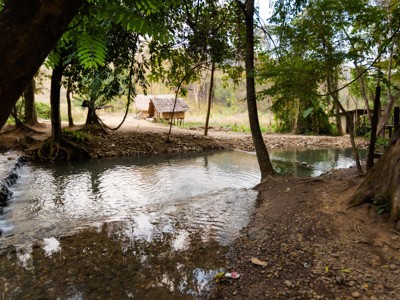 Rivier met doorwaadbare plek in het bos, met houten hutten aan de oever in Thailand.