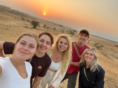 Groepsselfie tijdens Route India bij zonsondergang in een woestijnlandschap.