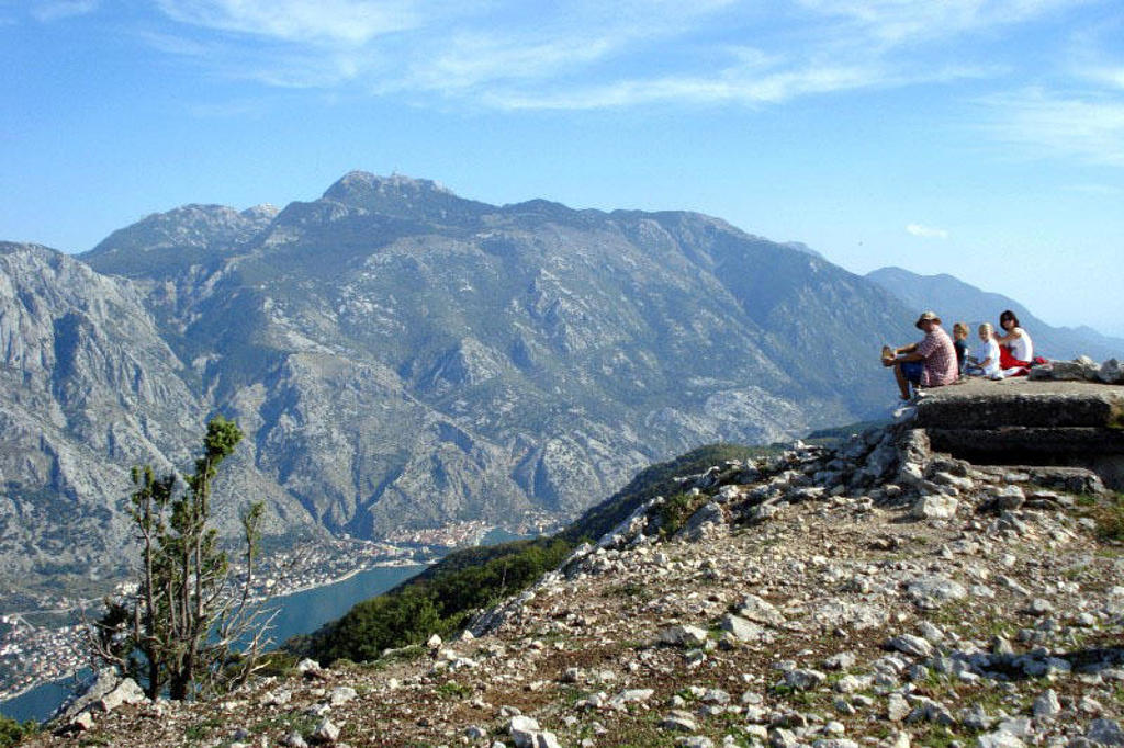 Uitzichtpunt boven de Baai van Kotor in Montenegro, met reizigers die uitkijken over bergen en zee.