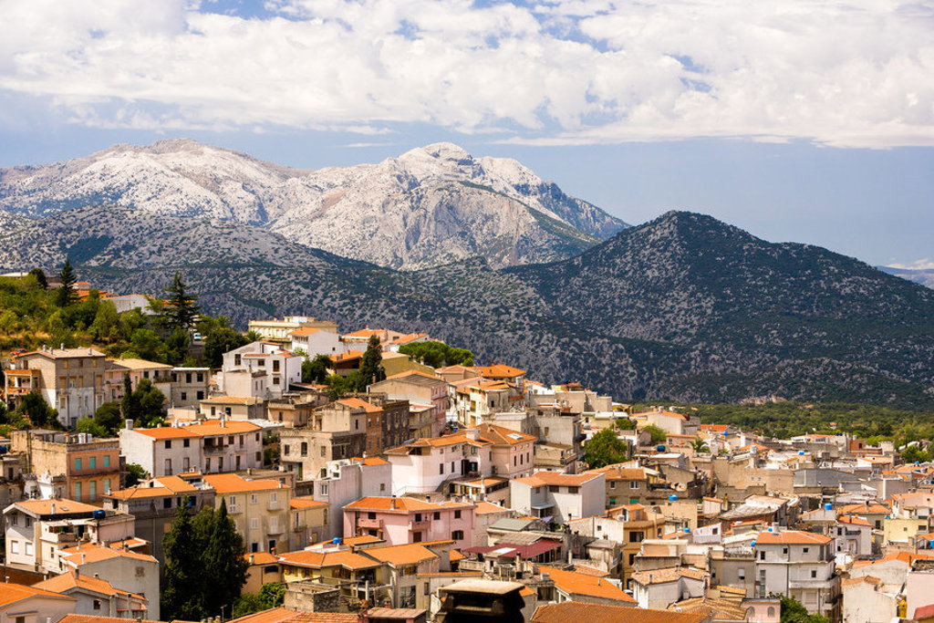 Bergdorp op Sardinië met oranje daken en uitzicht op ruige bergen tijdens een wandelvakantie in Italië.