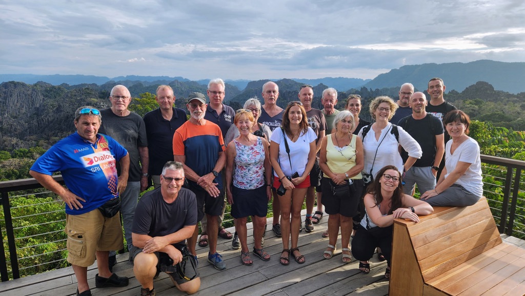 Groepsfoto van reizigers tijdens groepsrondreis Laos & Cambodja met uitzicht op karstbergen.