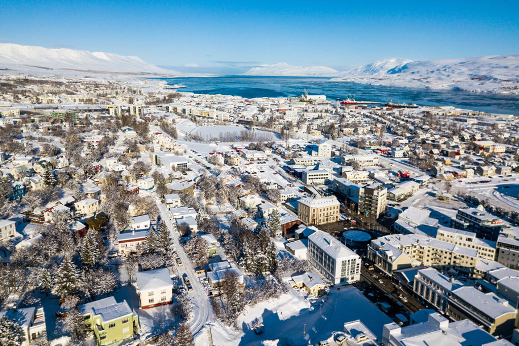 Sneeuwbedekte stad Akureyri aan het Eyjafjörður-fjord in Noord-IJsland, met bergen op de achtergrond.