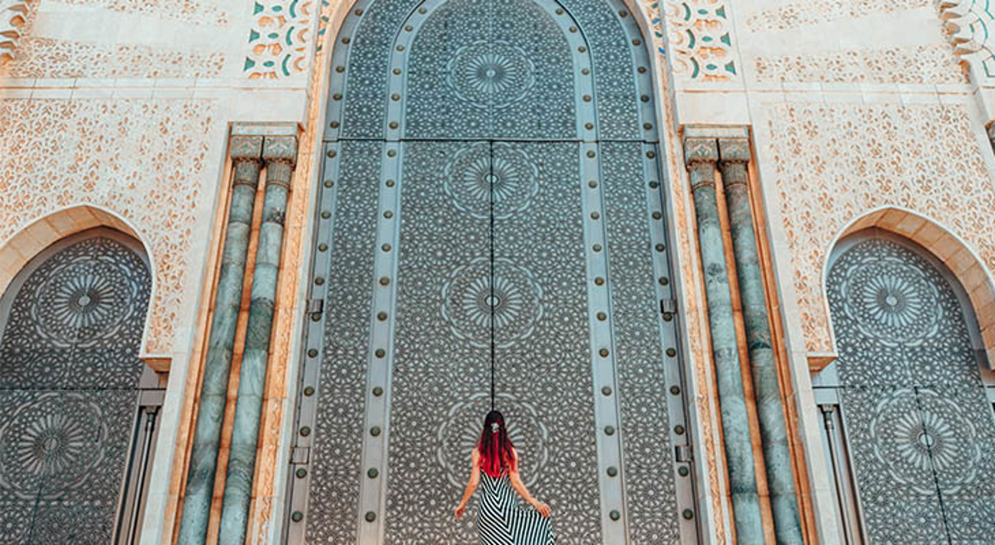 Casablanca Vrouw voor imposante, rijk versierde poort van de Hassan II-moskee in Casablanca, Marokko.