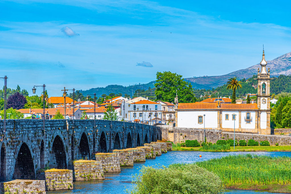 Stenen boogbrug over de rivier Minho bij Valença, Portugal, met kerk en bergen op de achtergrond.