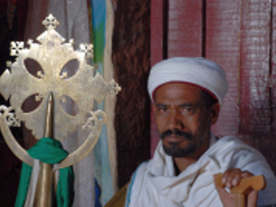 Ethiopisch-orthodoxe priester met kruis en processiekruis bij een kerkdeur in Ethiopië.