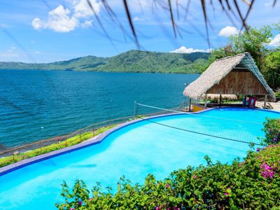 Infinitypool met rieten palapa aan het Meer van Nicaragua, met groen berglandschap op de achtergrond.
