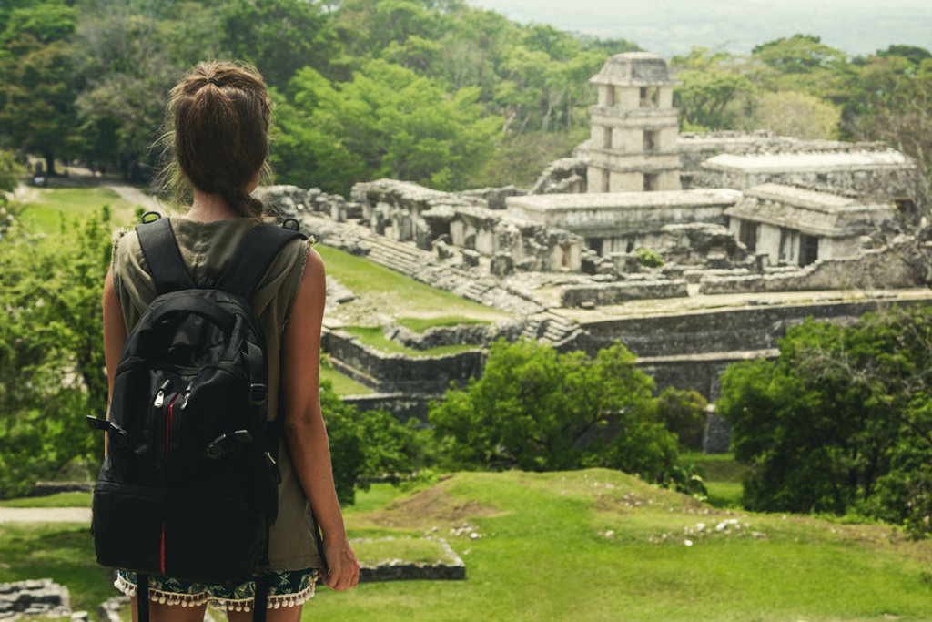 Rugzakreiziger kijkt uit over de Maya-ruïnes van Palenque tijdens een 22-35ers reis Mexico.