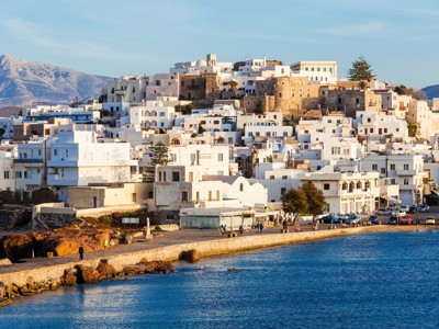 Witte huizen van Chora op Naxos langs de kust, met de Venetiaanse burcht bovenop de heuvel.