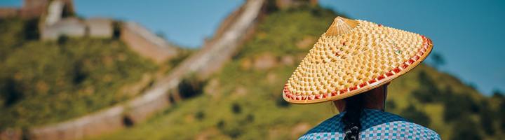 Persoon met strohoed kijkt uit over de Chinese Muur in China.