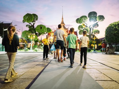 Gezin wandelt bij zonsondergang over het tempelplein in Bangkok, Thailand.