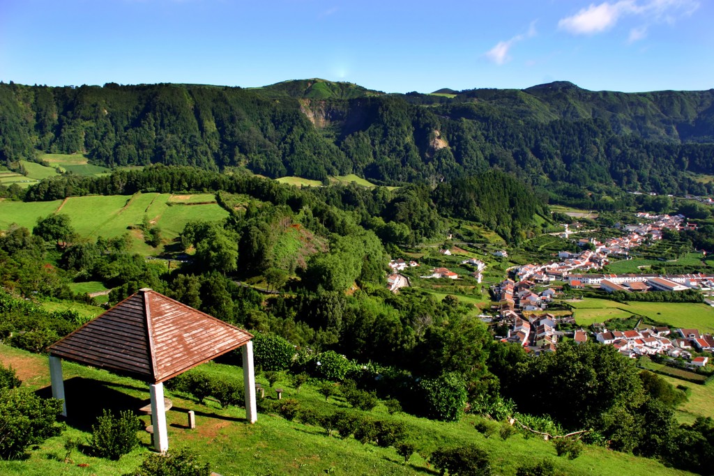 Uitzicht over een groen dal met dorp en bergen op de Azoren, Portugal.